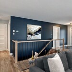 Salon moderne avec escalier et tableau abstrait.