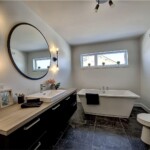 Salle de bain moderne avec baignoire et miroir rond.